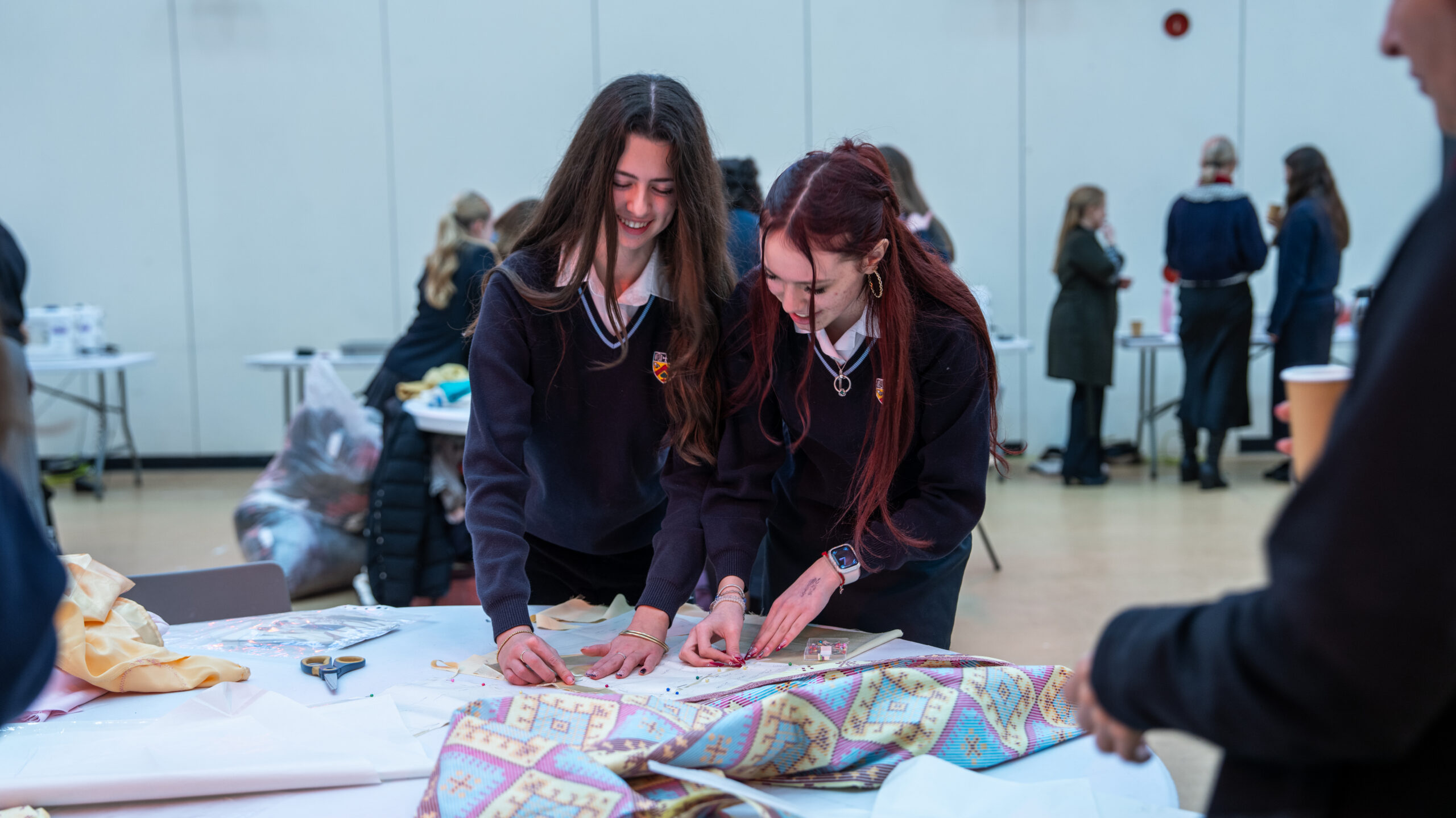 Two girls working together to pin fabric